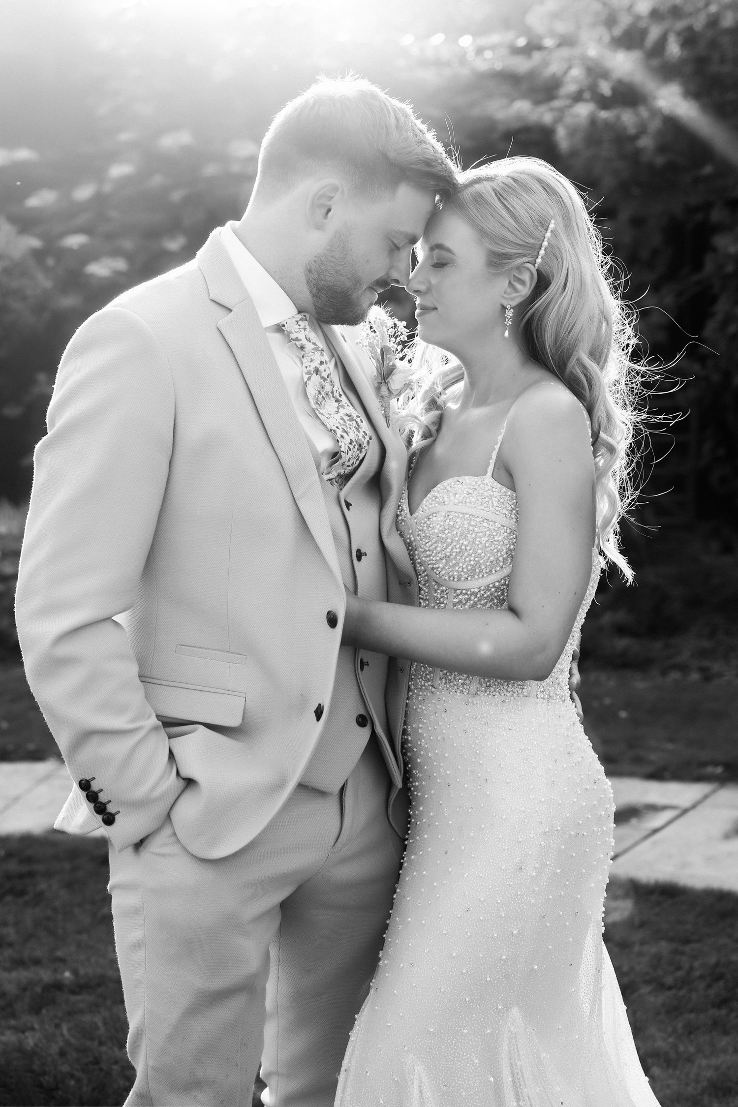 Black and white photo of a bride and groom sharing an intimate moment outdoors on their wedding day.