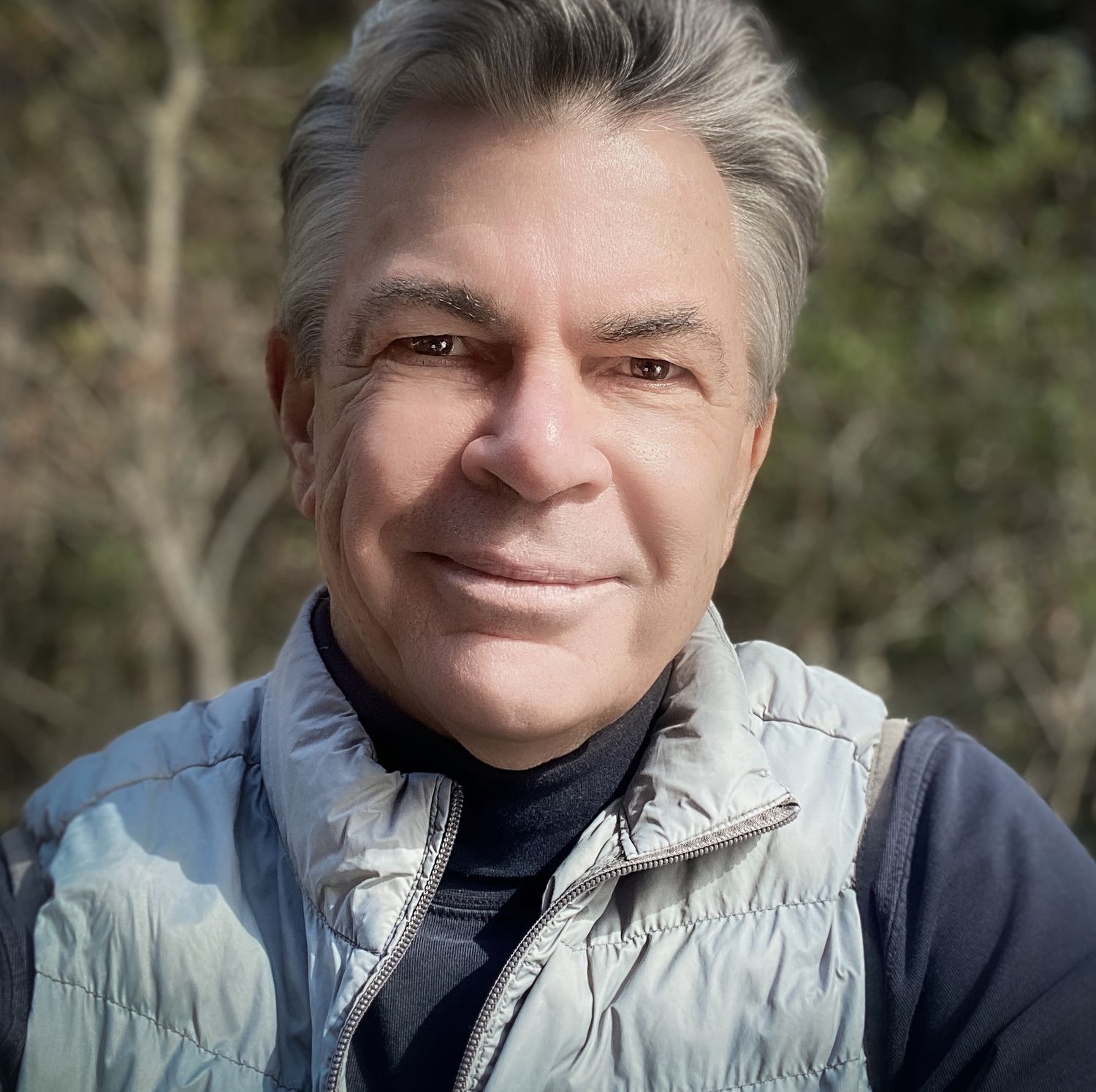A close-up portrait sequence showing four angles of someone wearing a light gray vest over a dark shirt outdoors.