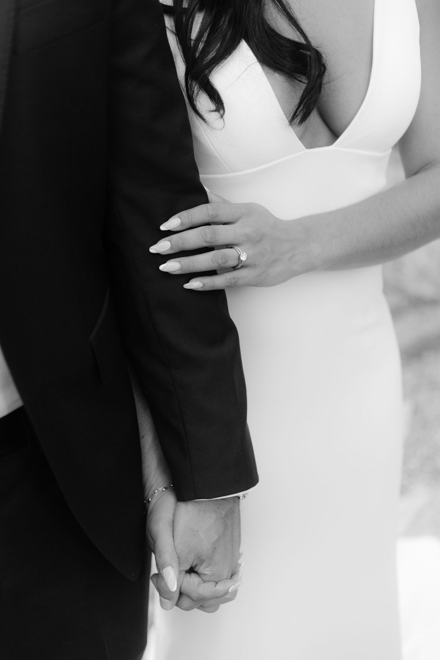 Hands of newlyweds intertwined, showcasing wedding rings, symbolizing love and unity