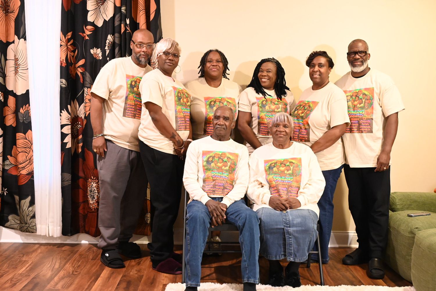 Group of people wearing matching white graphic t-shirts posing together for a family reunion photo indoors.