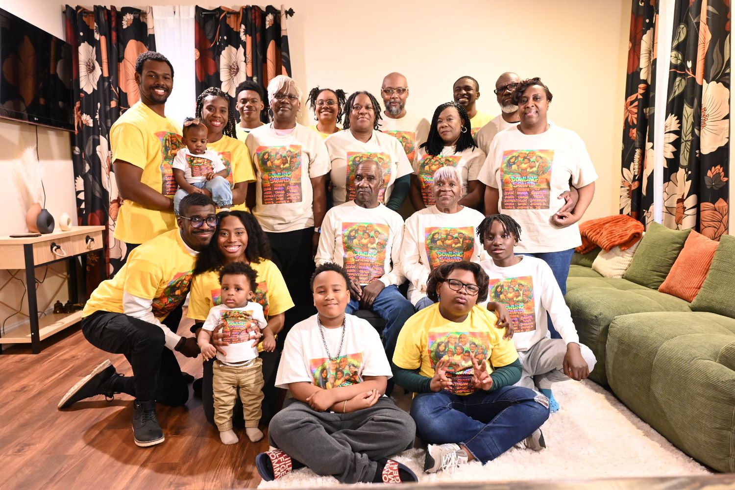 Large family group photo with adults and children wearing matching yellow and white custom t-shirts gathered in a living room.