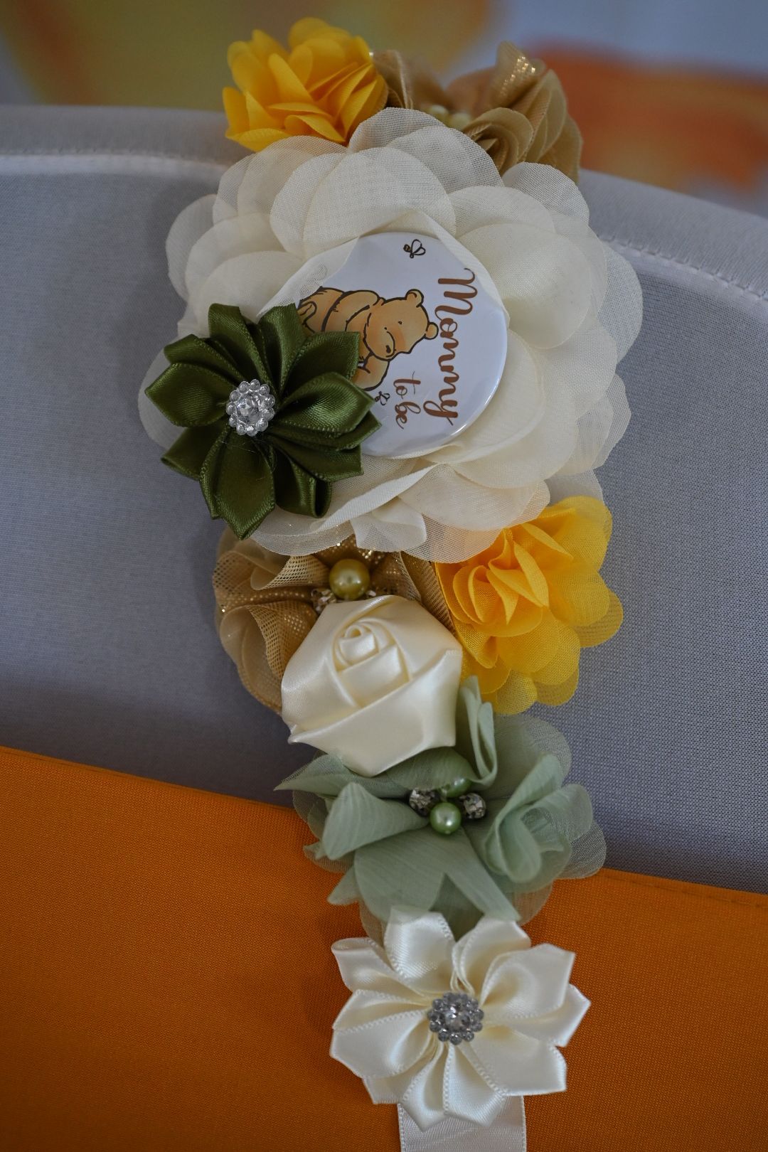 Mommy to be floral corsage with yellow, ivory, and sage green flowers featuring Winnie the Pooh tag.