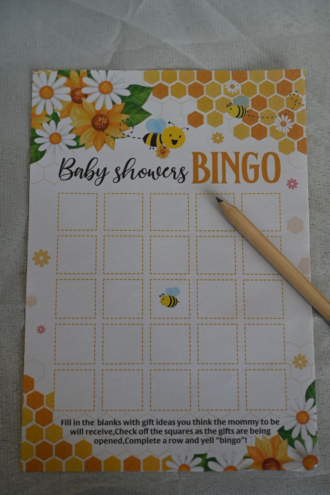 Bee-themed Baby Shower Bingo card with honeycomb design, daisy flowers, and a pencil.
