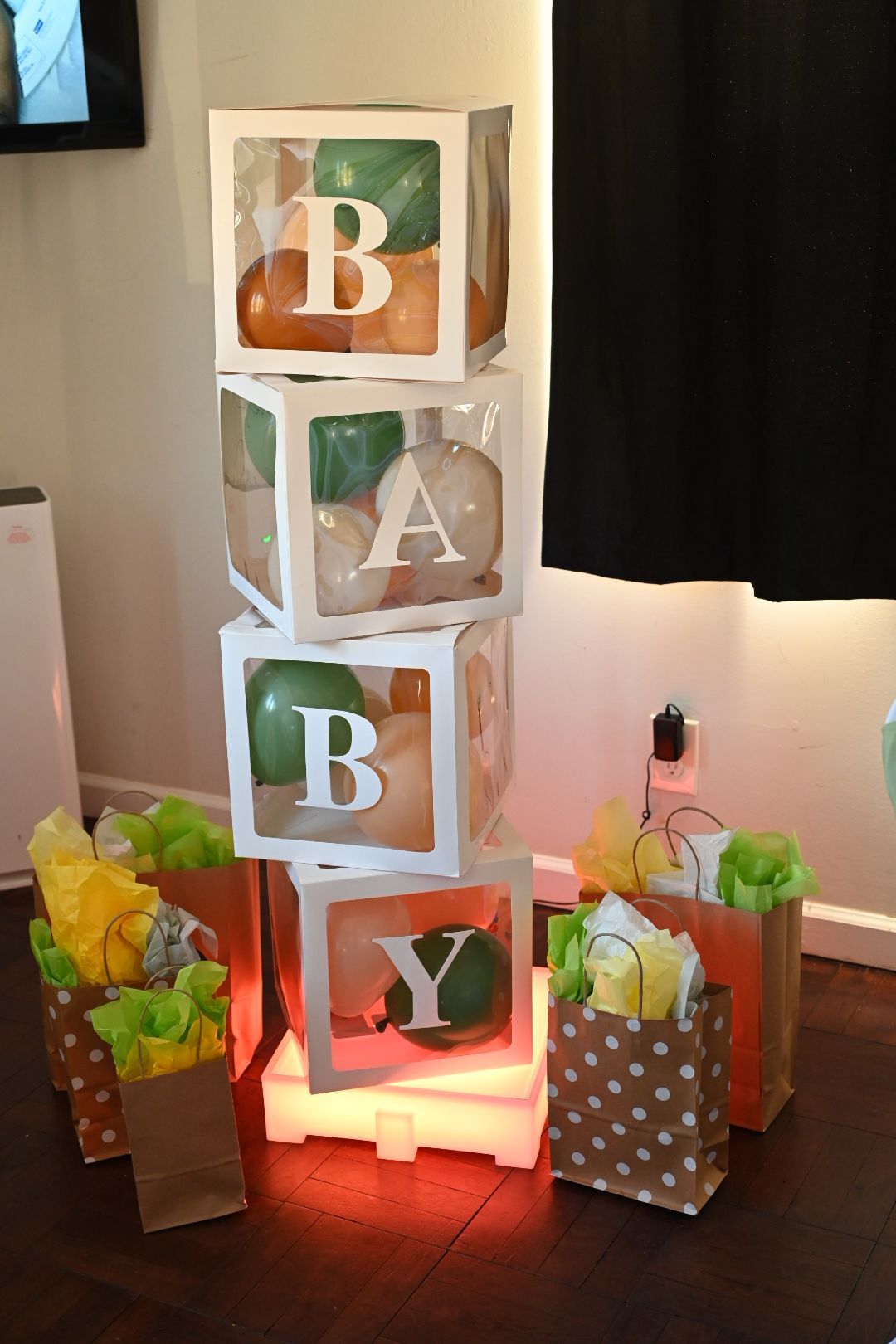 Light-up BABY letter blocks filled with colorful balloons surrounded by polka dot gift bags.