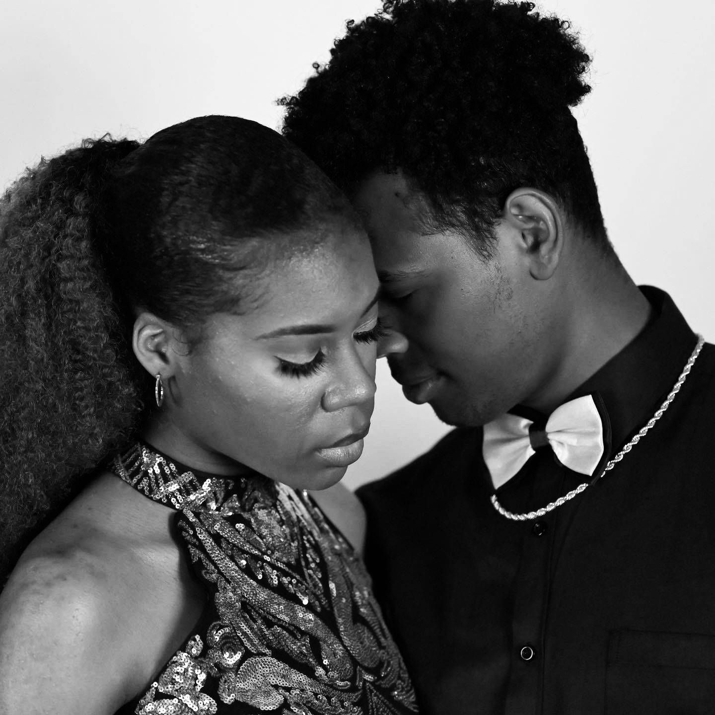 Black and white intimate portrait of a couple with foreheads touching closely.