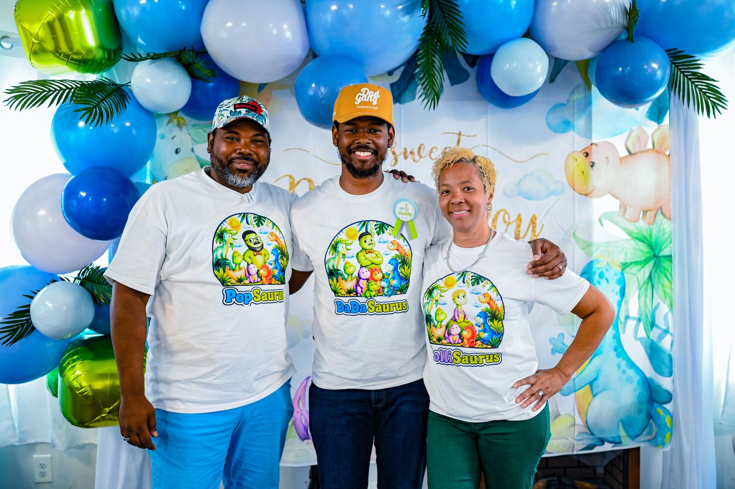 Three people wearing matching custom t-shirts at a tropical themed party with balloon arch.