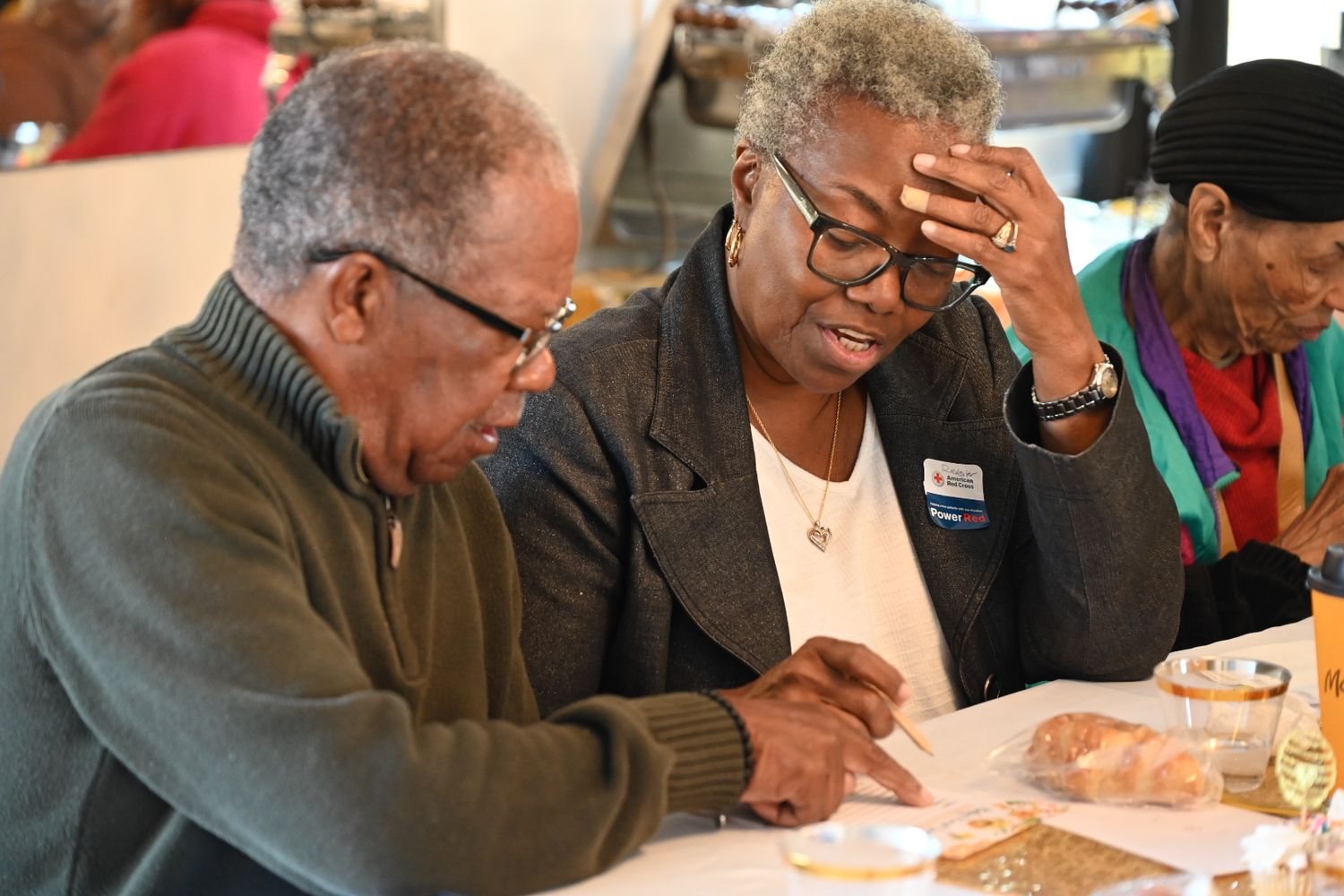 Two elderly guests read a document together at a festive baby shower celebration.