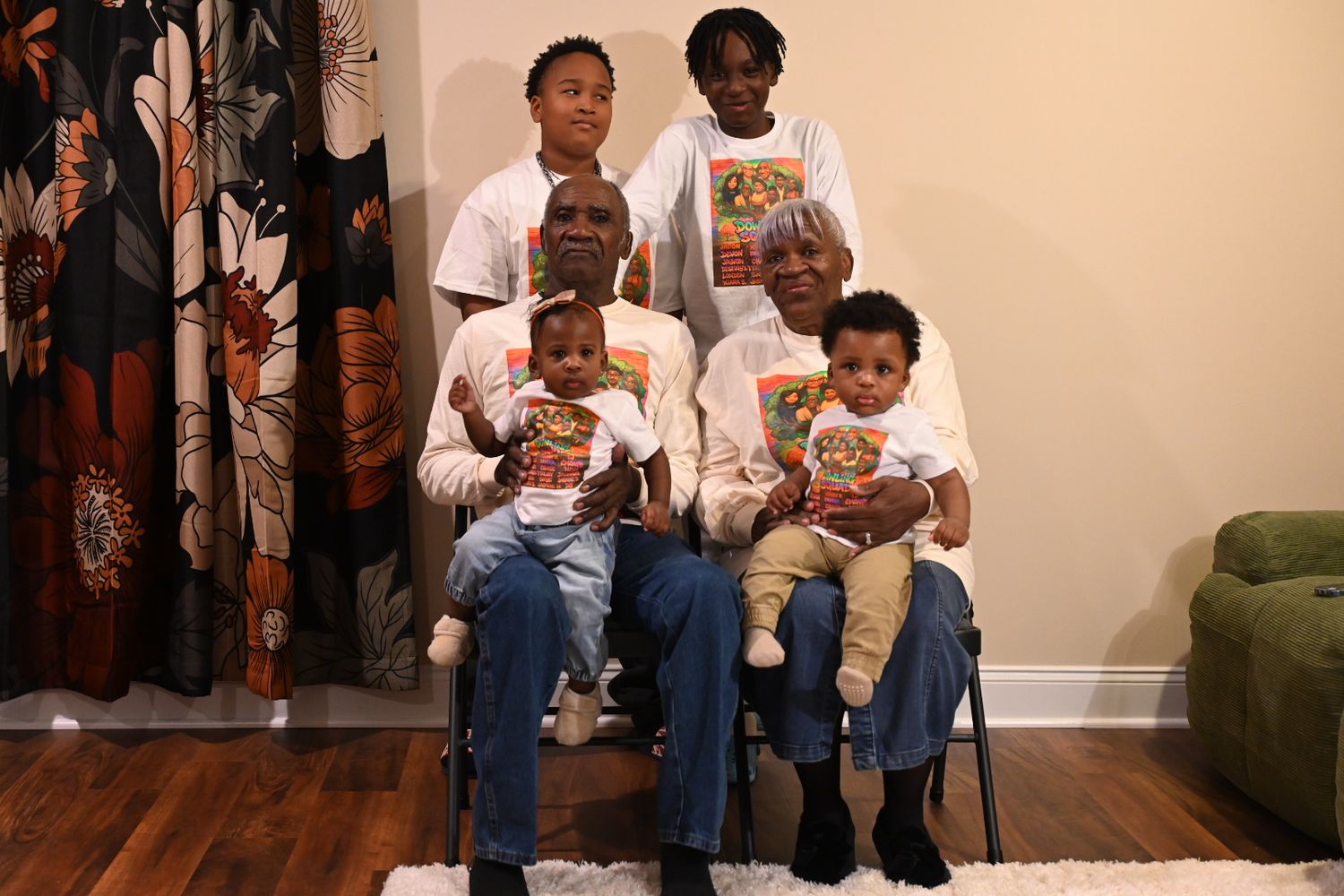 Family portrait with six members holding colorful books, posing together in a cozy living room setting.