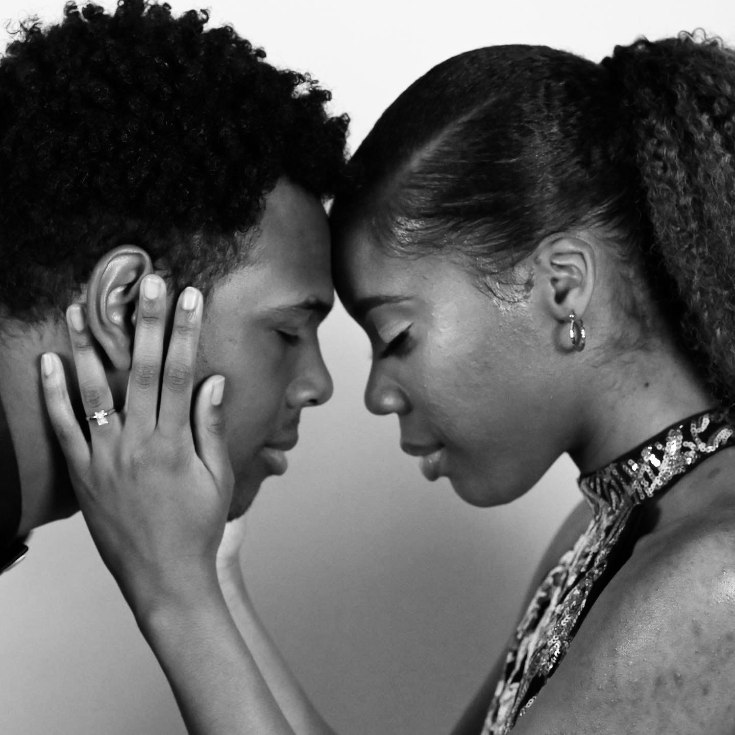 Black and white close-up of a couple gently touching foreheads in an embrace.