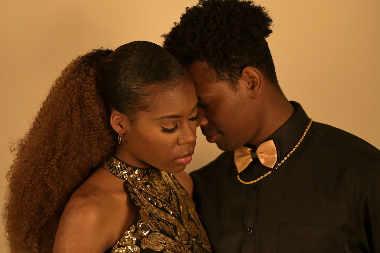 Black couple shares intimate forehead touch moment in golden-toned romantic portrait.