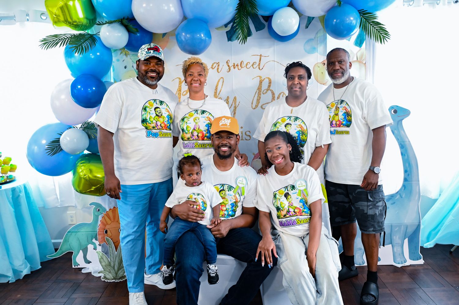Large family group photo at a sweet baby boy dinosaur-themed birthday celebration.