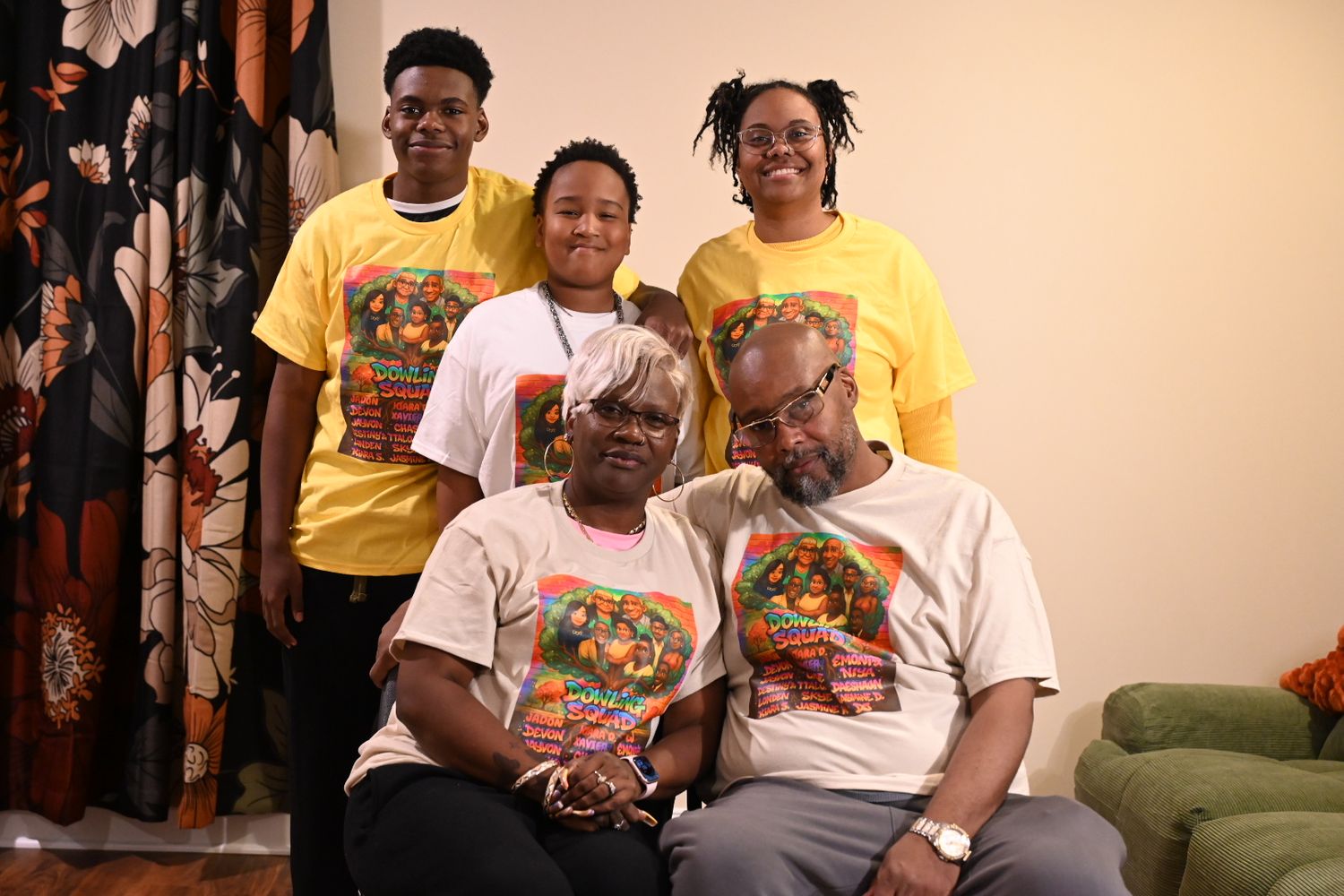 Family of five posing together in matching yellow and white graphic t-shirts, smiling for a group photo indoors.