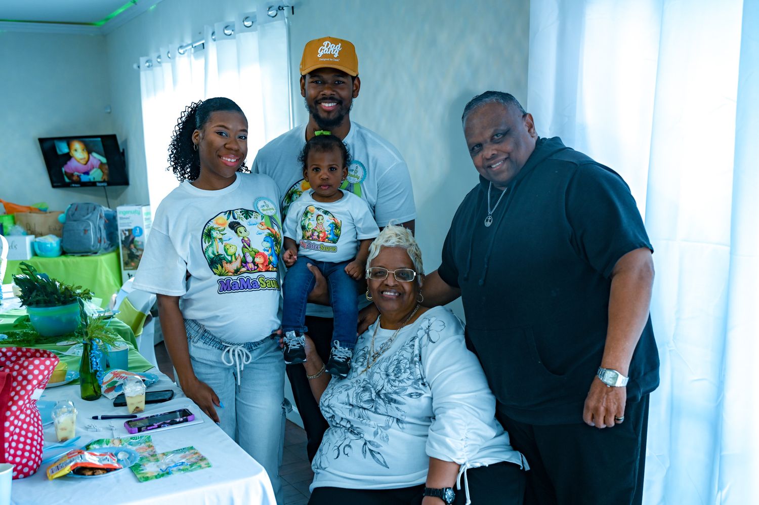 Family group smiling together indoors at a baby boy birthday party celebration.