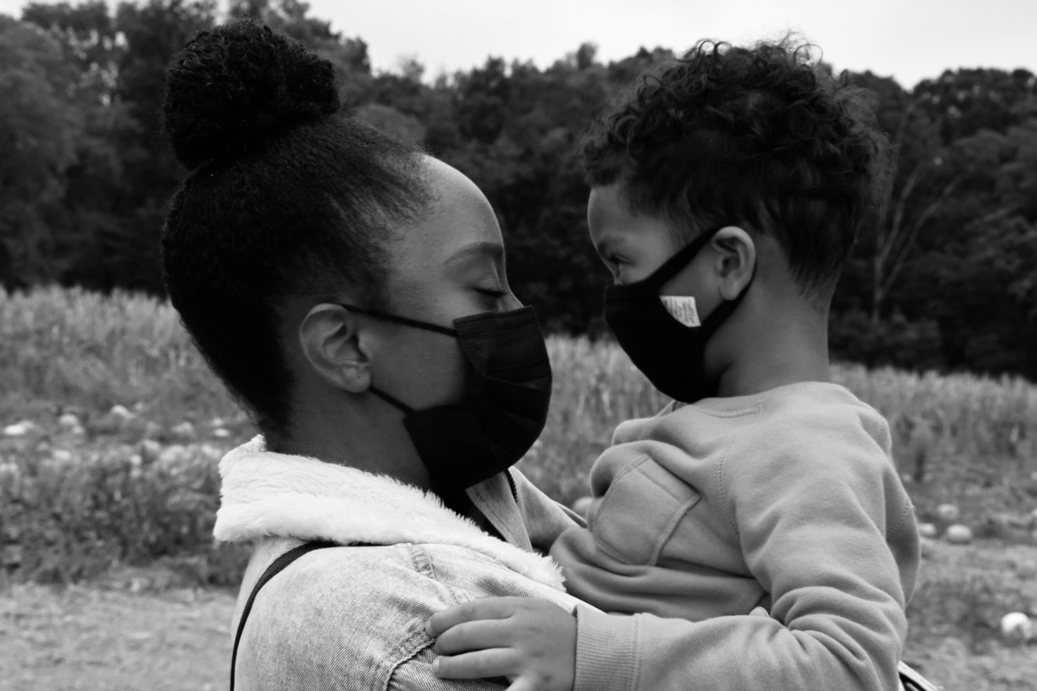Black and white photo of a mother and child wearing face masks outdoors.