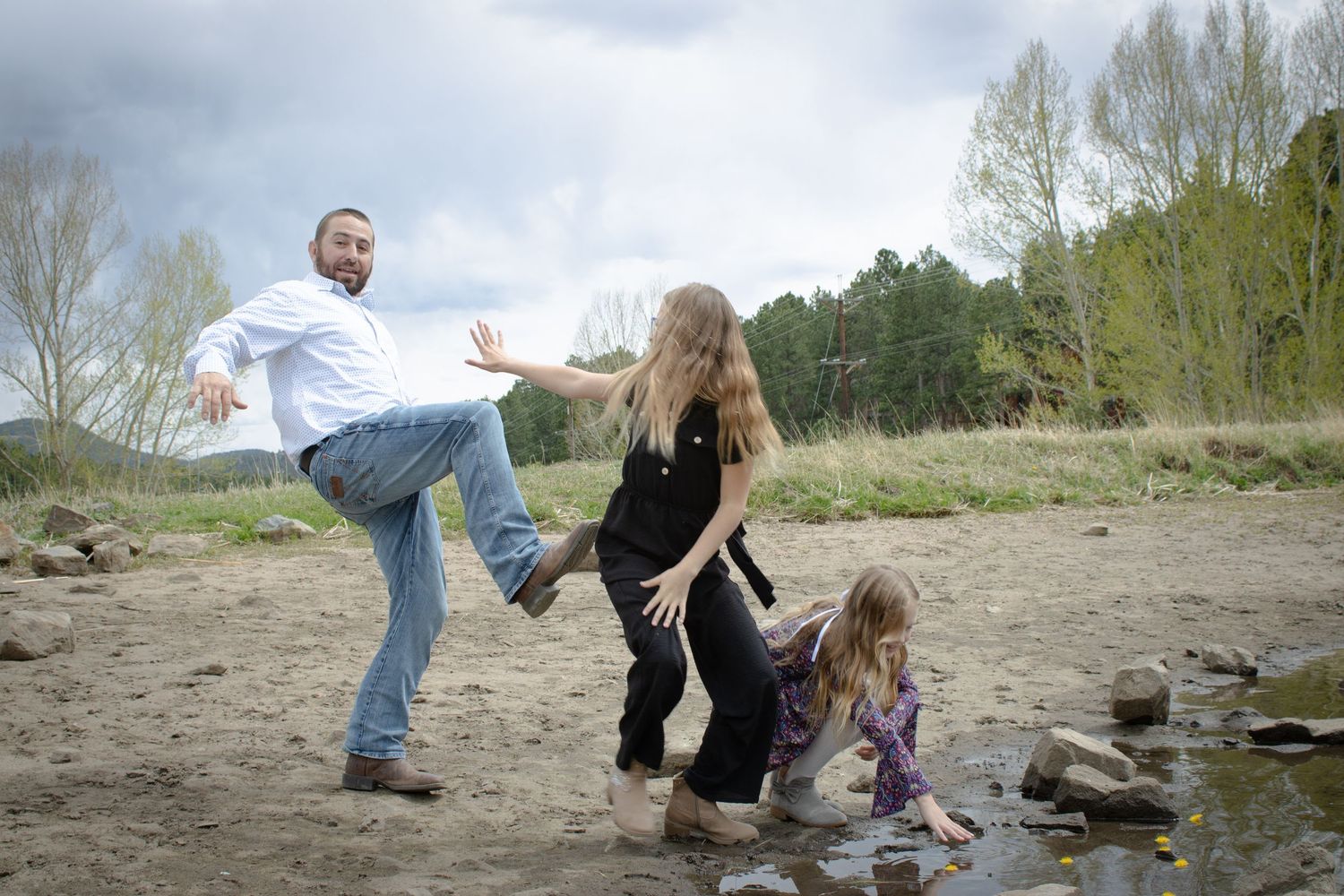 Family playing near a rocky creek bed, with parents and young child enjoying outdoor fun.