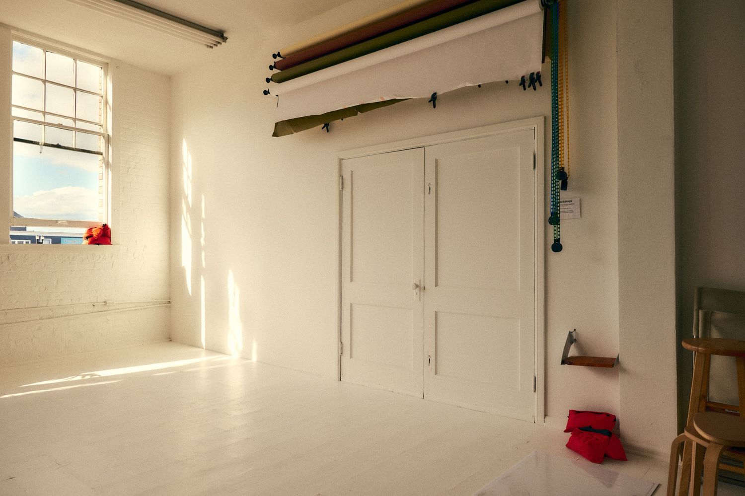 Bright white photography studio interior with white walls, floors, and natural window light.