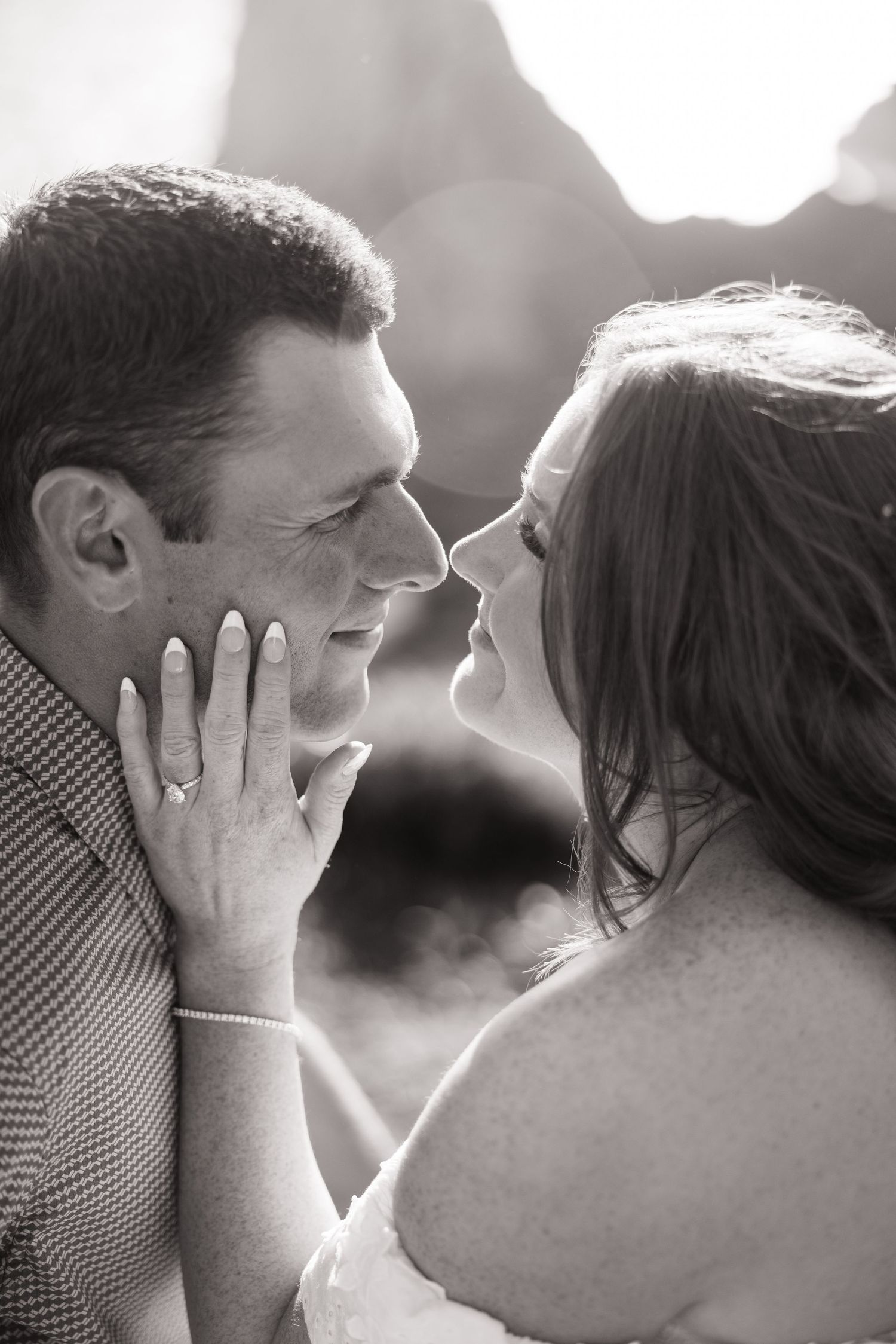 Black and white close-up of couple gazing at each other, woman tenderly holding mans face.