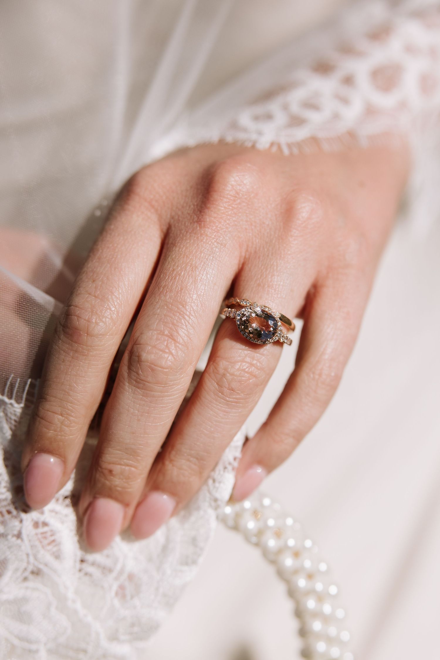 Close-up of a bride's hand wearing a vintage-style ring with a dark gemstone on her wedding day.