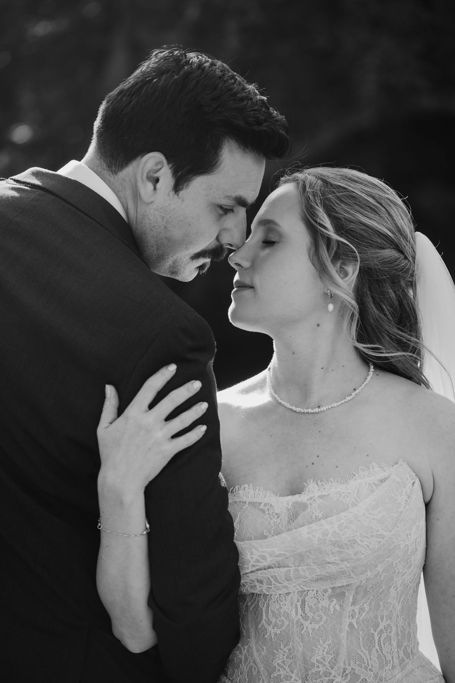 Black and white intimate portrait of bride and groom sharing a tender moment before their first kiss.