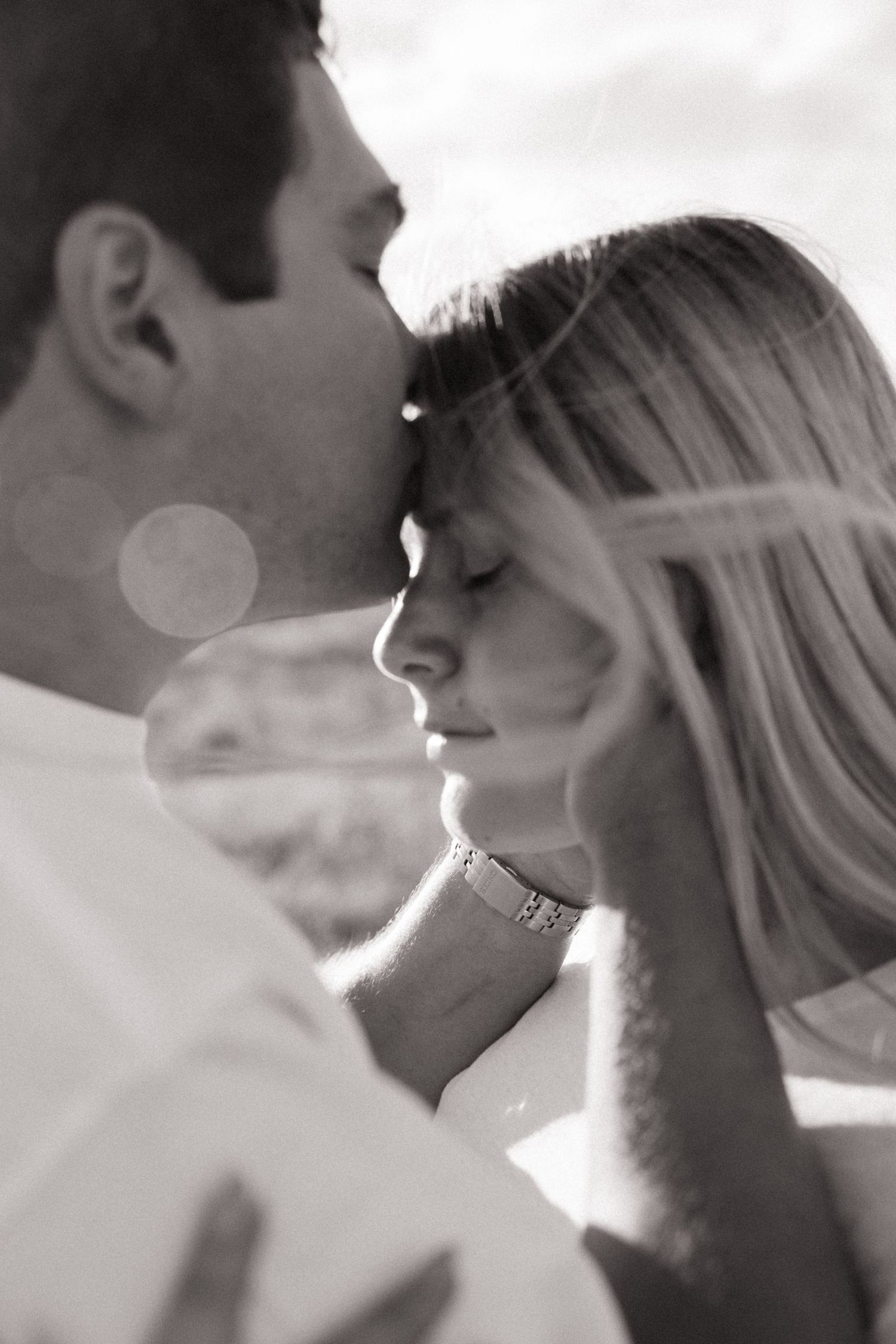 Romantic black and white close-up of couple sharing a tender kiss outdoors.