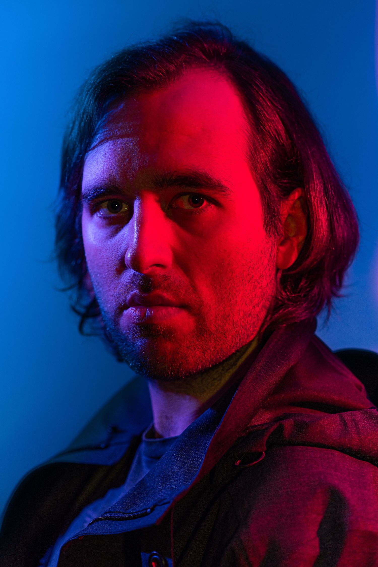 Dramatic portrait with red and blue lighting creating a moody atmosphere.