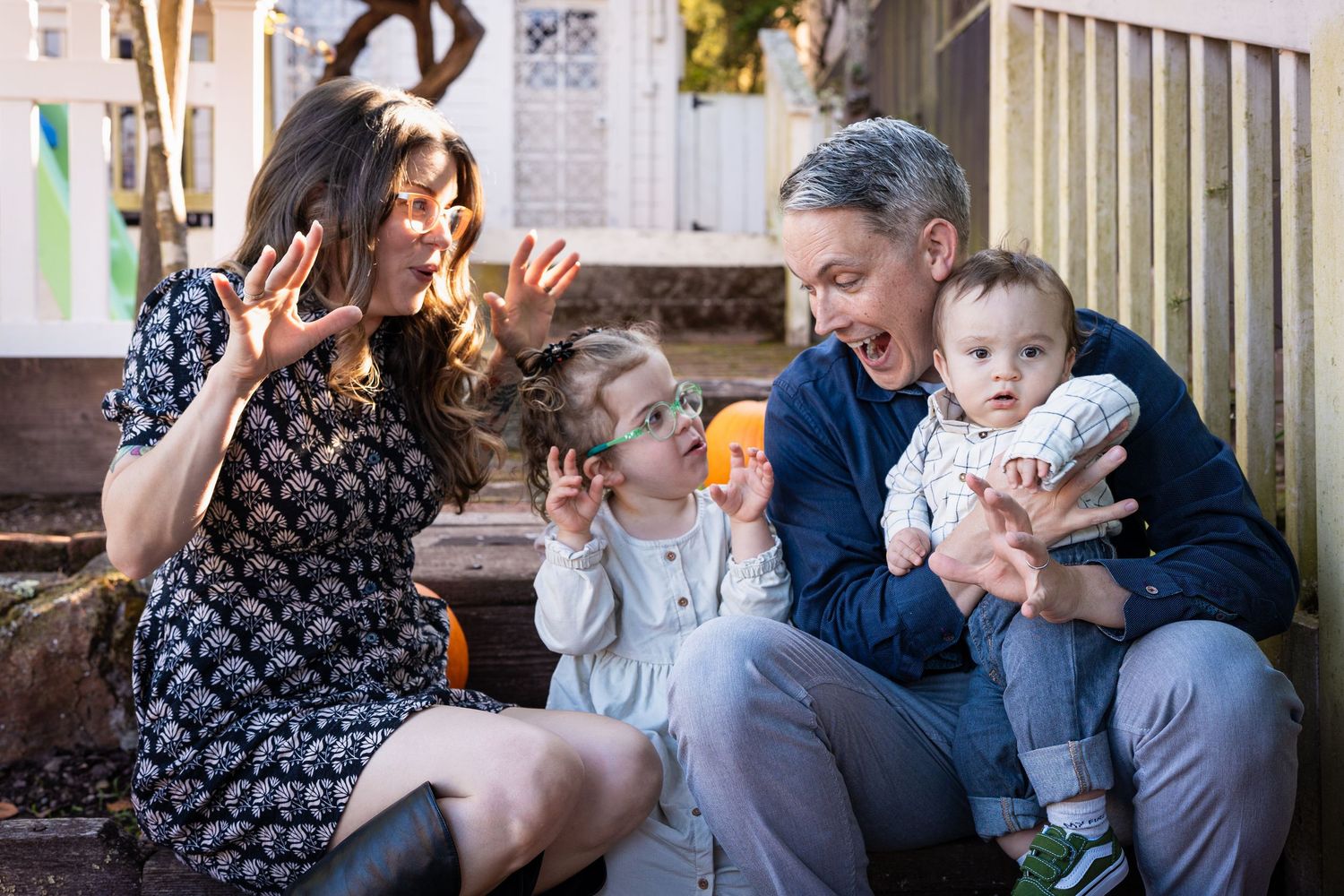 A happy family sits together on outdoor steps during a casual autumn photoshoot.