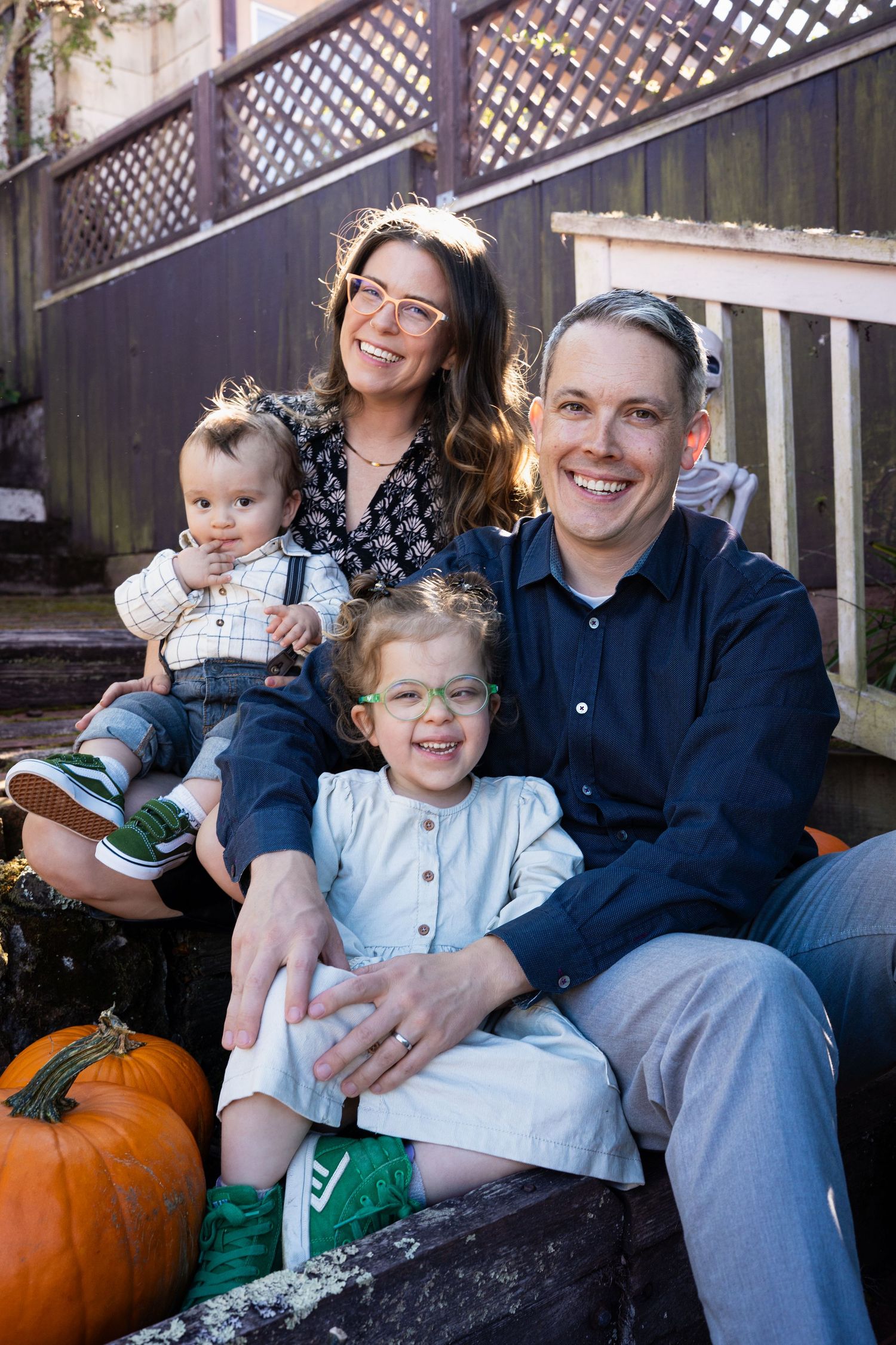 A series of four candid outdoor family photos with pumpkins and lattice backdrop showing relaxed autumn moments.
