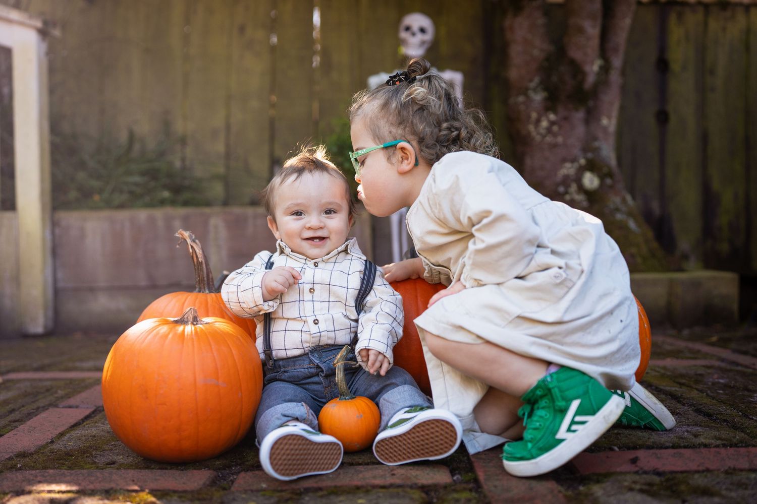 Children explore and play with large orange pumpkins on rustic wooden steps during autumn.