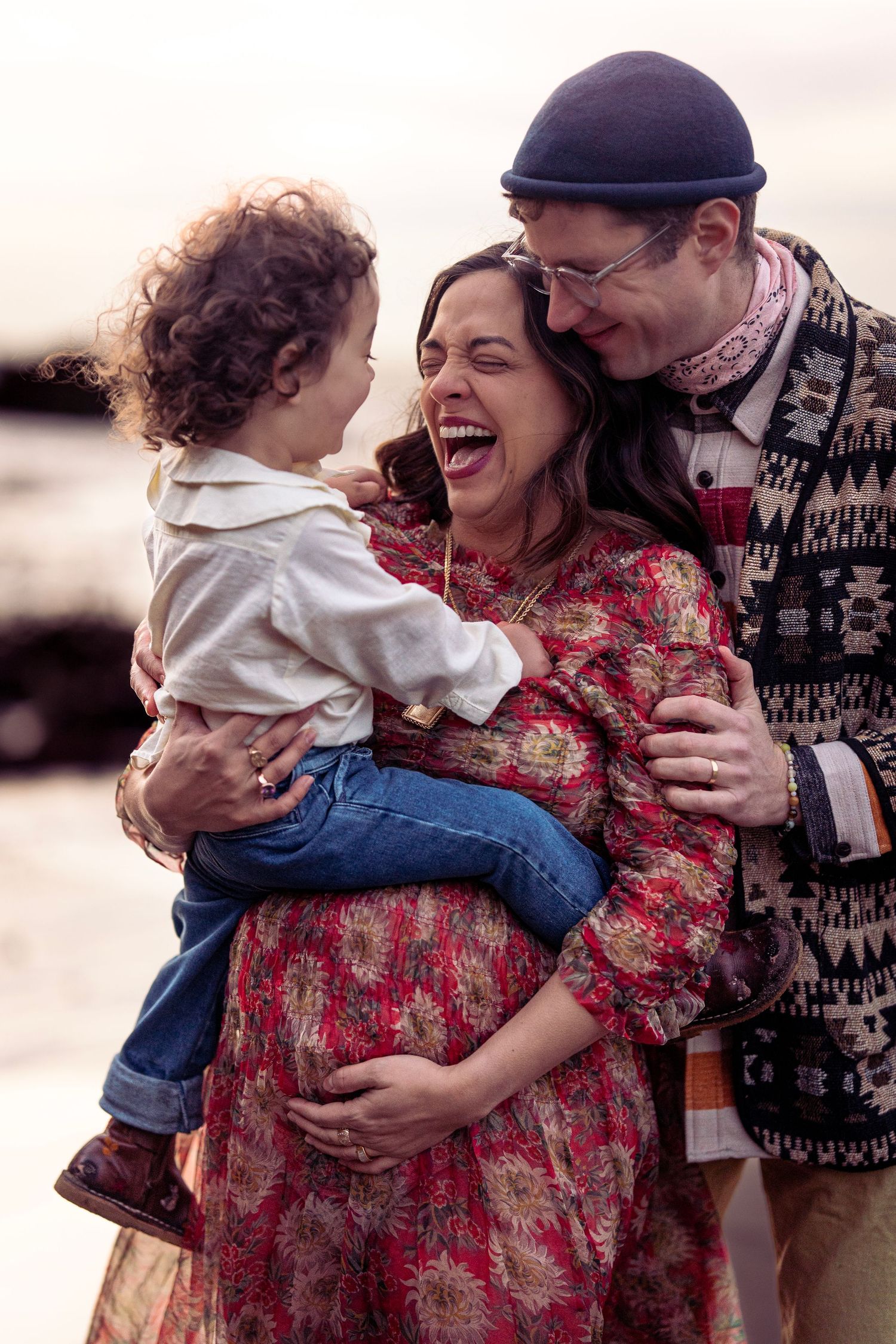 Family shares intimate moment of laughter on beach at sunset.