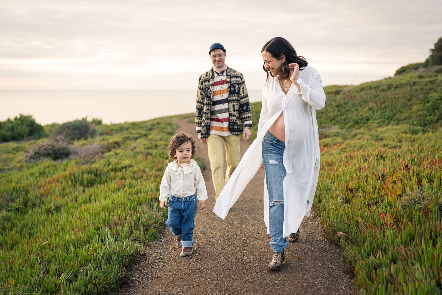 A family enjoying a scenic hike together along a coastal trail during golden hour.