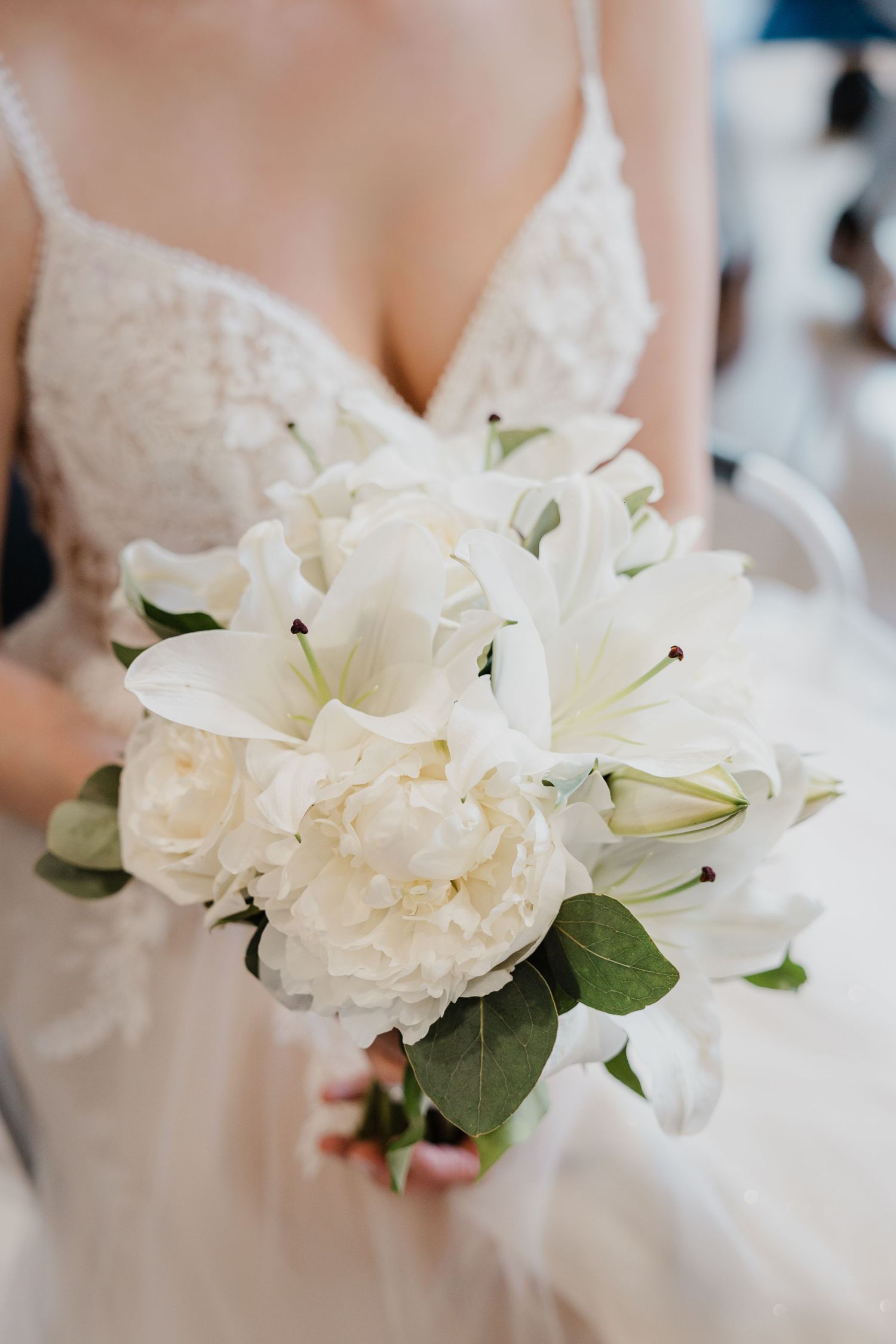 Élégant bouquet de mariée blanc composé de lys et de pivoines avec une verdure délicate.