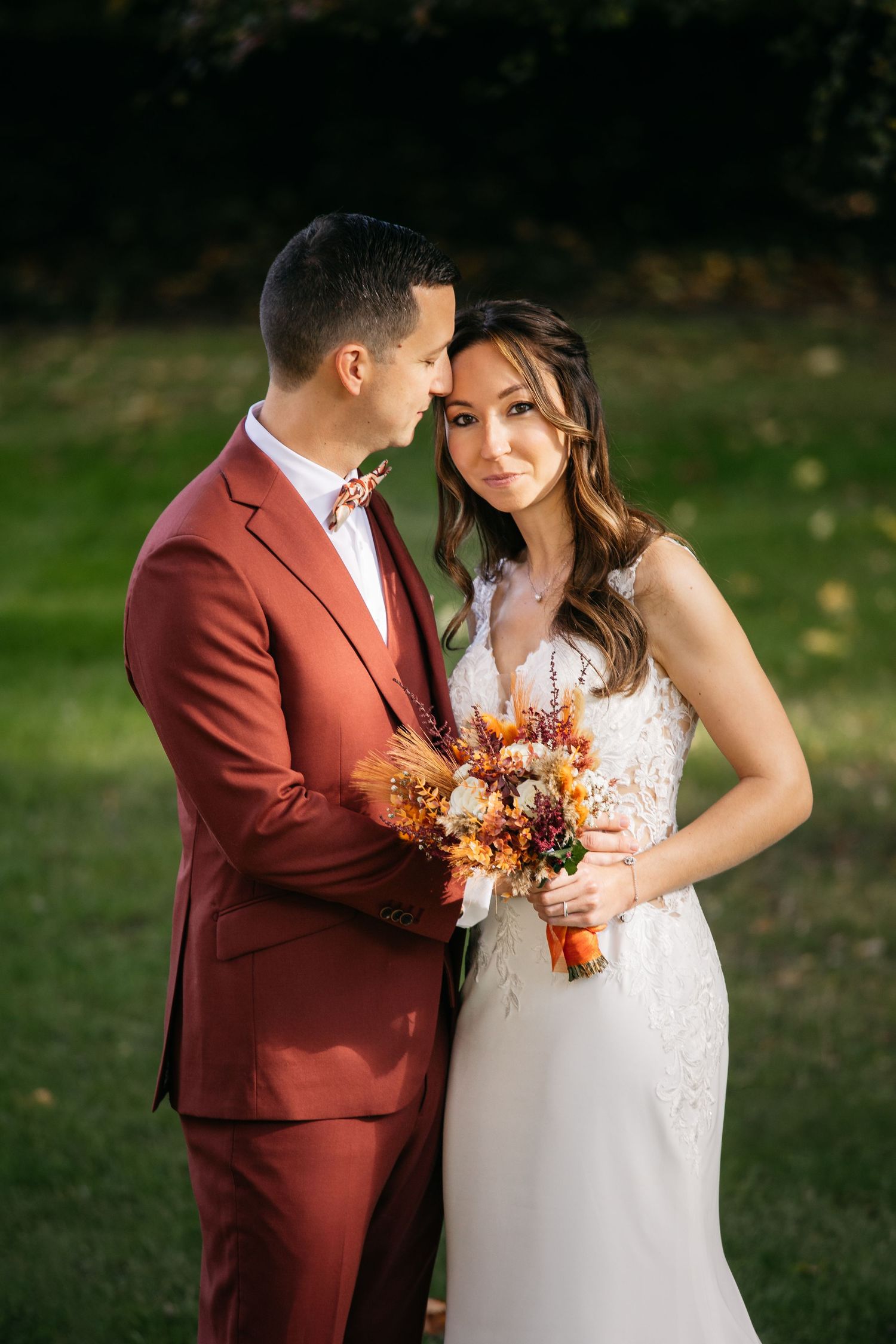 Une série de photos de mariage d'automne romantique mettant en vedette un couple en costume bordeaux et une robe en dentelle blanche.