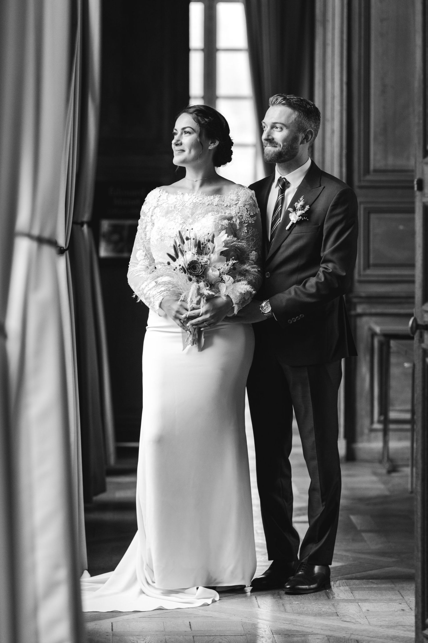 Série de photos de mariage en noir et blanc montrant un couple élégant posant dans un couloir orné avec de hautes fenêtres et des colonnes.