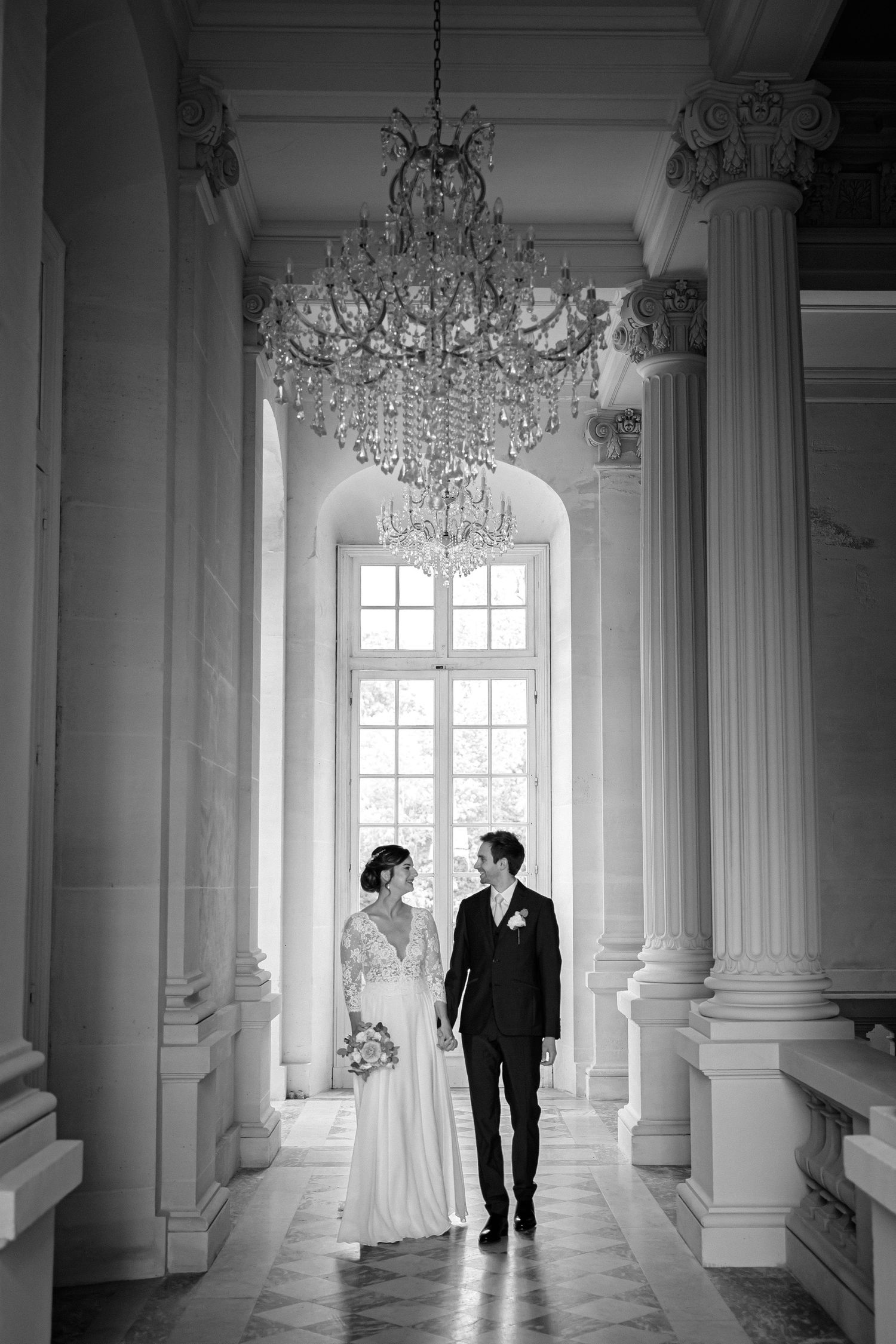 Une séquence de photos de mariage romantique en noir et blanc montrant les silhouettes d'un couple dans un couloir élégant avec des lustres.