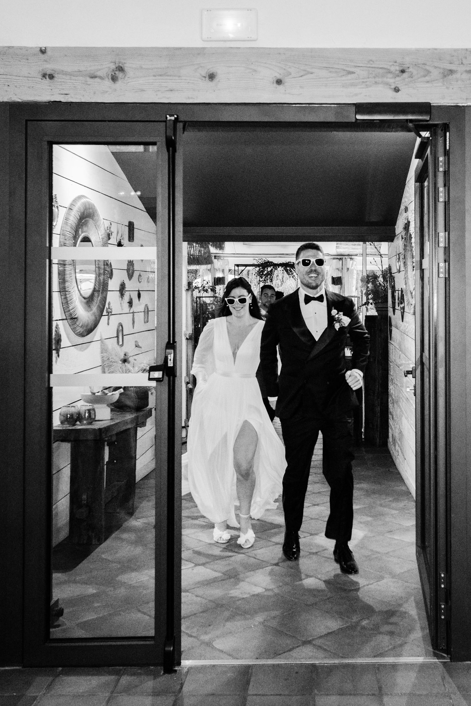 Séquence en noir et blanc d'une fête de mariage marchant dans un couloir moderne.