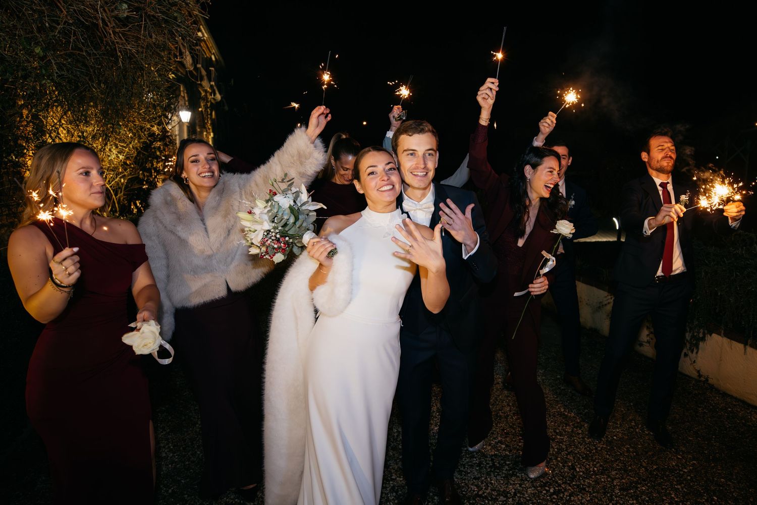 Les invités de mariage dansent et célèbrent avec des cierges magiques lors d'une réception nocturne en plein air.