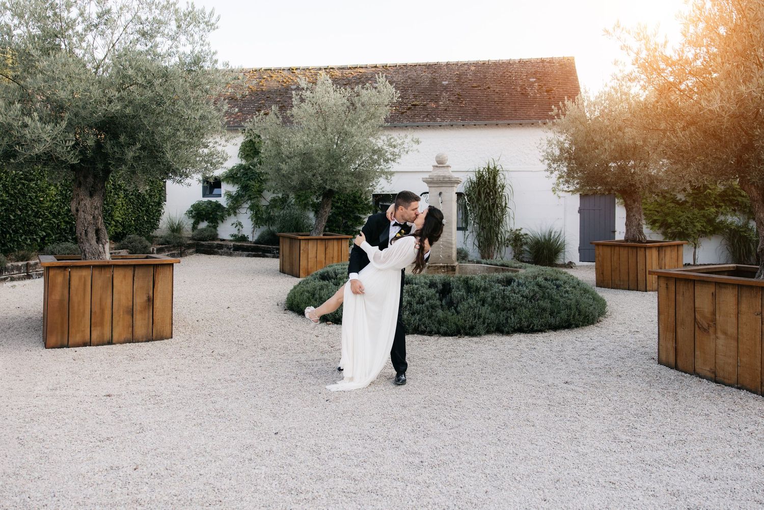 Espace de cérémonie de mariage en plein air élégant avec portes en bois et décorations florales blanches sur un chemin de gravier.