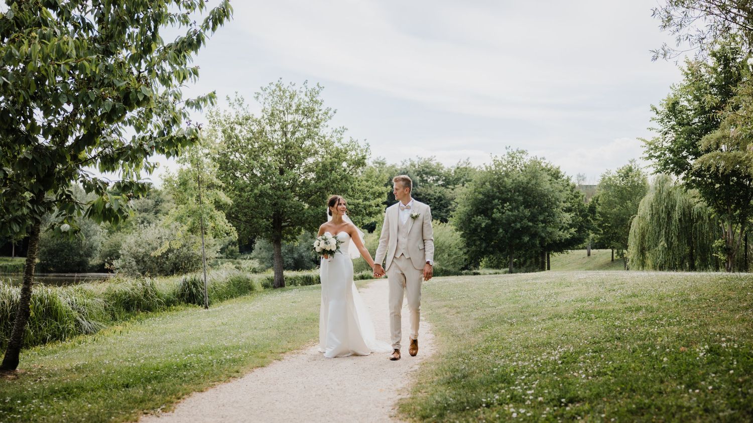 Un couple marchant ensemble sur une colline herbeuse dans un jardin extérieur romantique pendant l'été.