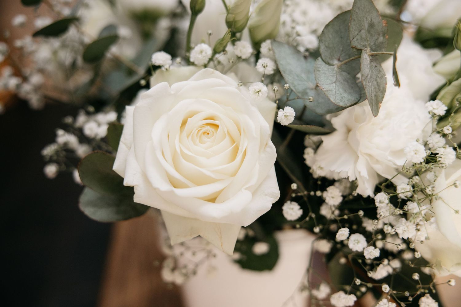 Gros plan sur un bouquet de roses blanches avec du gypsophile et des feuilles d'eucalyptus pour un arrangement de mariage.