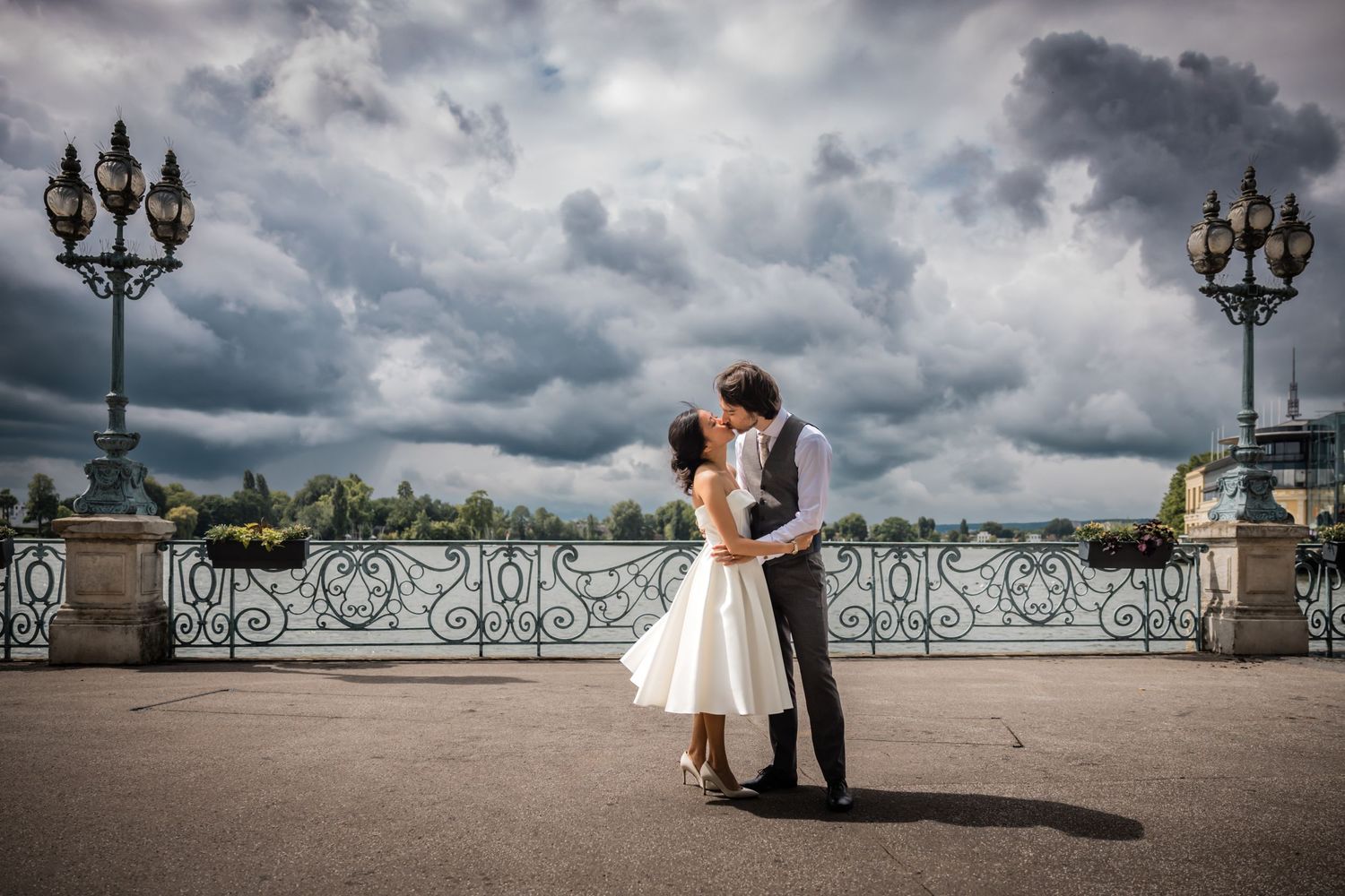 Un couple habillé avec élégance pose de manière romantique sur un point de vue panoramique avec des balustrades ornées et des nuages orageux