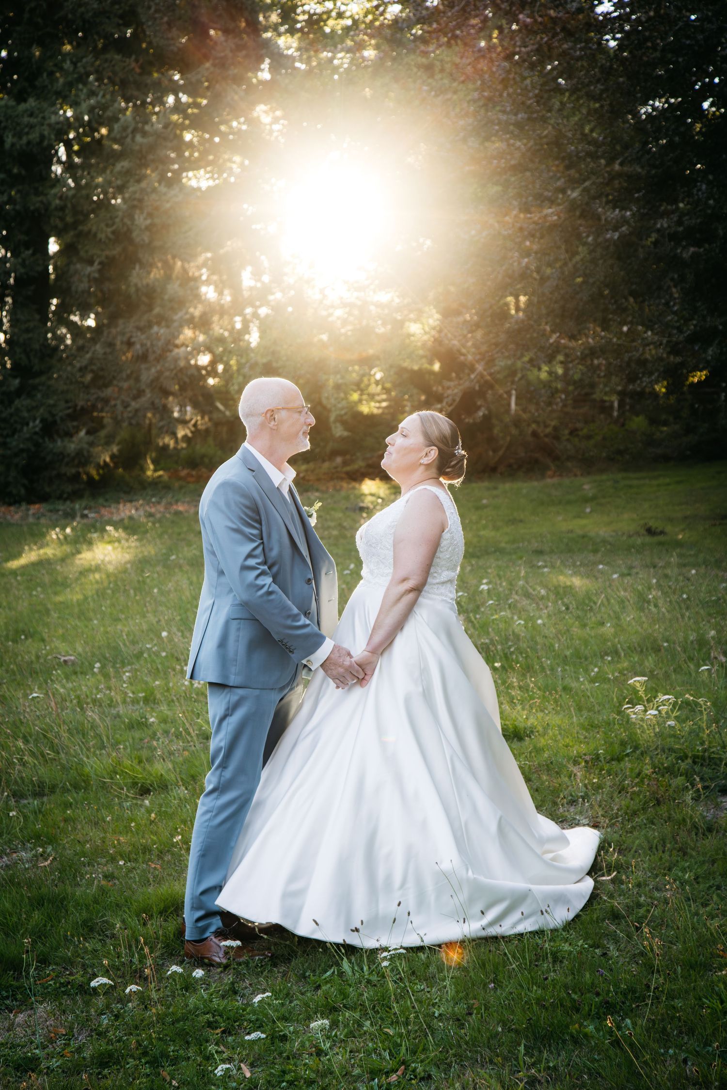 Un couple de mariés romantiques partage des moments intimes dans une prairie ensoleillée pendant la séance de photographie de l'heure d'or.
