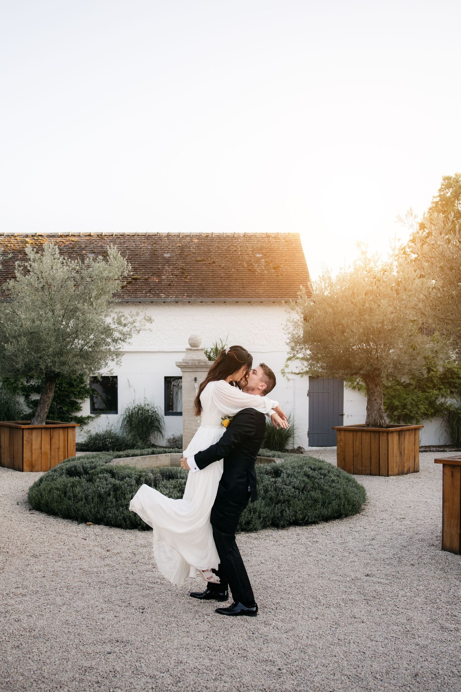 Couple de mariés dansant et plongeant dans une cour extérieure romantique au coucher du soleil.