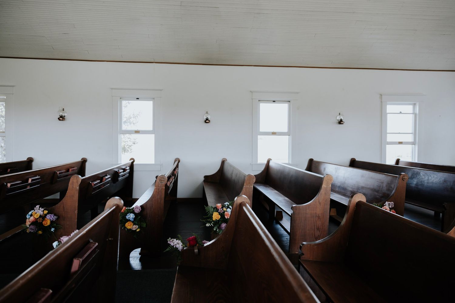 Interior view of empty wooden church pews with natural light streaming through windows in a historic sanctuary.