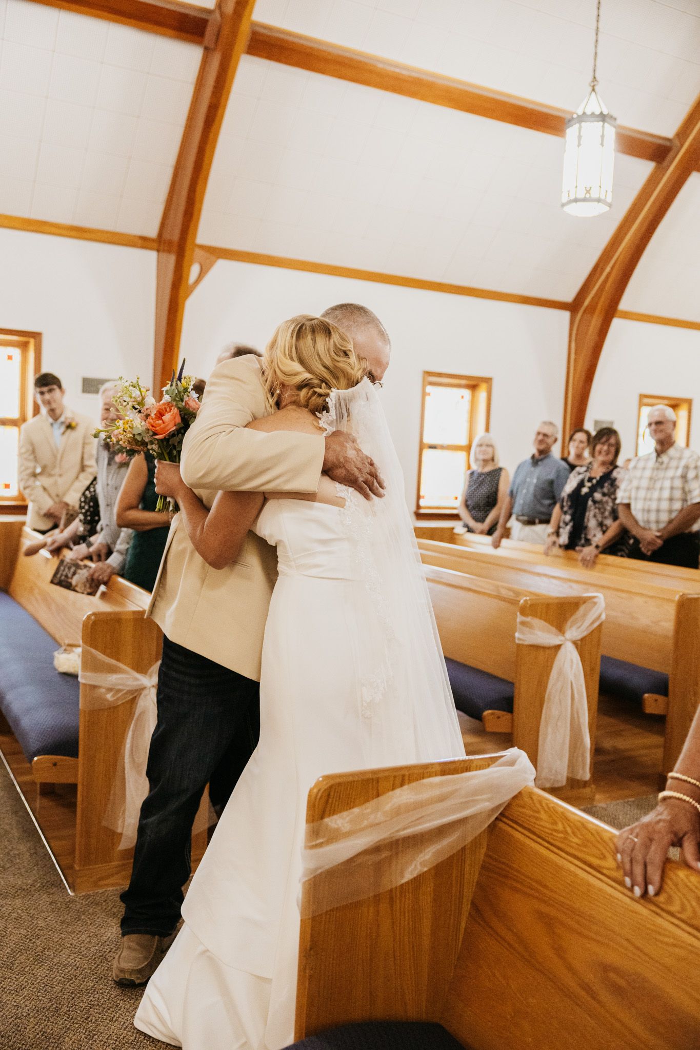 Bride and groom share an emotional hug at the altar inside a wooden chapel during their wedding ceremony.