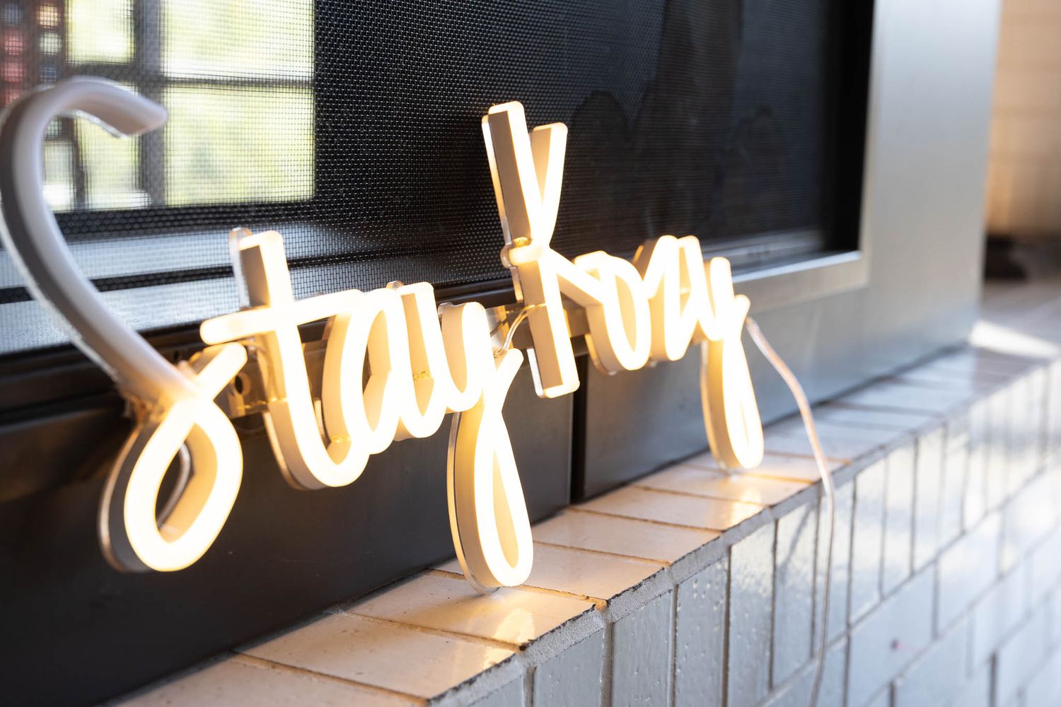 Illuminated white neon script sign mounted on a dark wall creates an elegant glowing display.