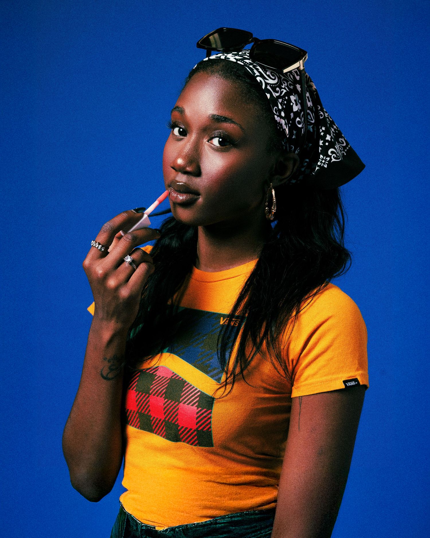 Portrait series against blue backdrop featuring person in yellow top and crown accessory striking different poses.