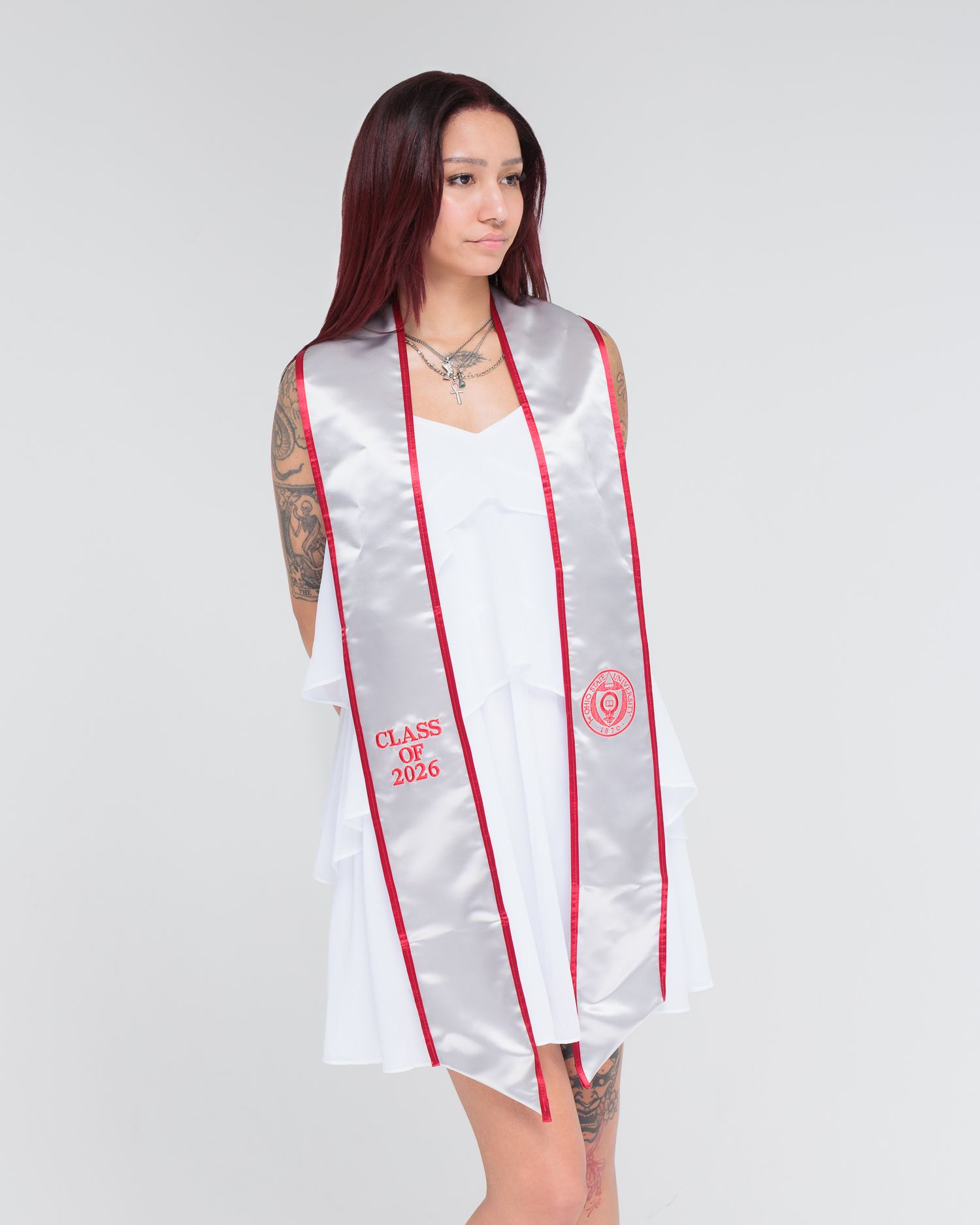 Woman wearing a white dress with a silver and red Class of 2016 graduation sash stole over her shoulders.
