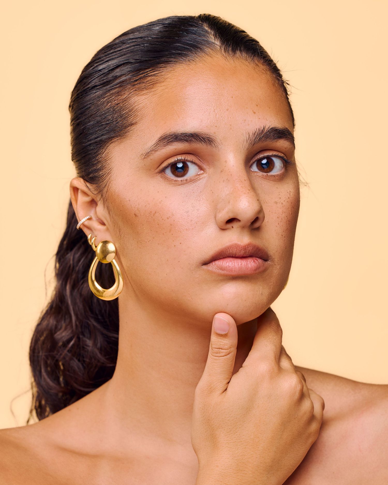 Artistic beauty portrait series showing close-up facial features against a warm peach-colored background.
