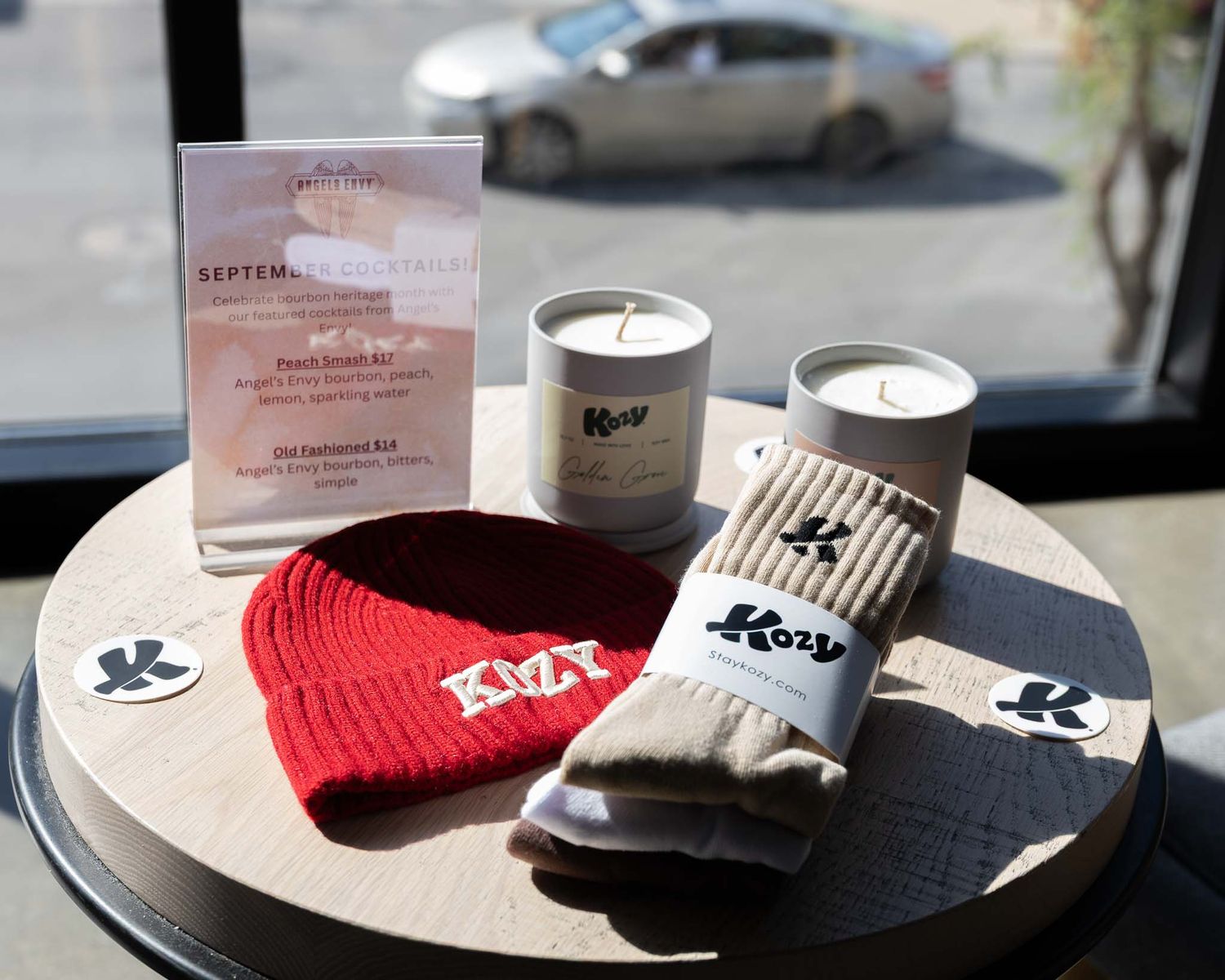 A collection of winter accessories including red beanie hats and socks displayed on a wooden surface with candles.