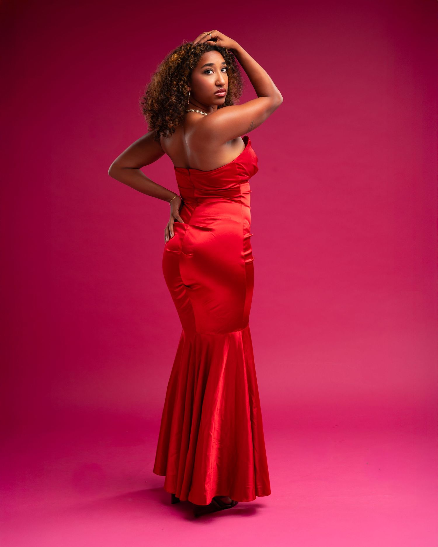 A figure in a flowing red dress strikes dynamic dance poses against a vibrant pink studio backdrop.